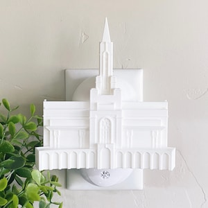 May include: White plastic nightlight shaped like a temple. The nightlight plugs into a standard electrical outlet.