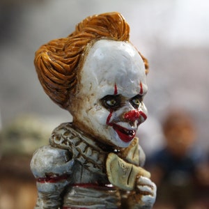 Puede incluir: Primer plano de una figura de payaso con maquillaje rojo y blanco, pelo naranja y una sonrisa de dientes. La figura lleva un cuello de volantes blanco y rojo.