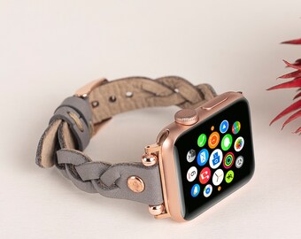 May include: Rose gold Apple Watch with a gray braided leather band. The watch face displays colorful app icons. The band features rose gold hardware and a braided design, adding a stylish touch to the wearable technology.