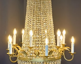 May include: A gold-toned chandelier with crystal accents and multiple candle-style light bulbs. The chandelier has a bell-shaped design with a decorative top.
