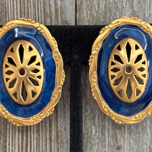 May include: A pair of gold-tone oval-shaped earrings with a blue enamel center and a gold cutout design.