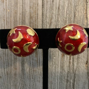 May include: A pair of red and gold earrings with a moon and star design.