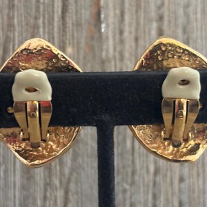 Pu&ograve; includere: Un paio di orecchini vintage a clip. Ogni orecchino presenta un design a forma di diamante dorato con una superficie strutturata. Il meccanismo a clip &egrave; dorato con un cuscinetto color crema per il comfort.