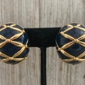 May include: A pair of gold and blue clip-on earrings. The earrings are round and have a geometric design with gold accents.
