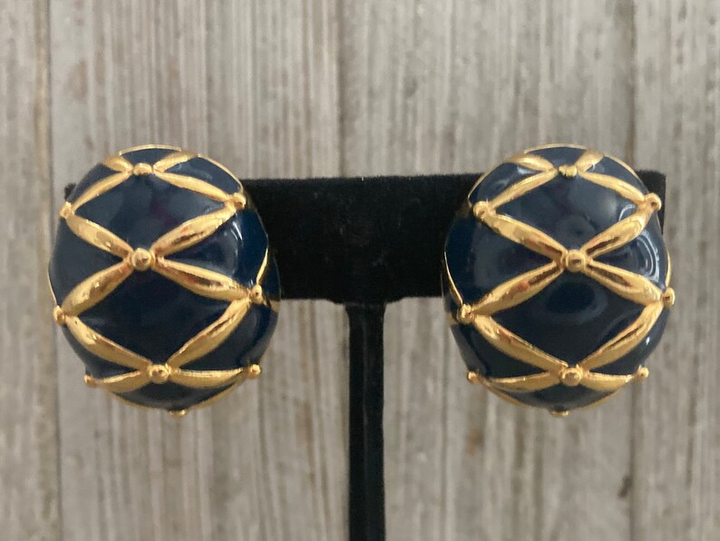 May include: A pair of gold and blue clip-on earrings. The earrings are round and have a geometric design with gold accents.