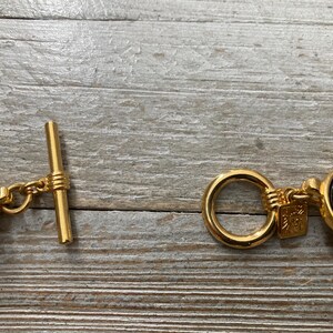 Pode incluir: Pulseira em tom dourado com pedras ovais pretas e fecho de correr.