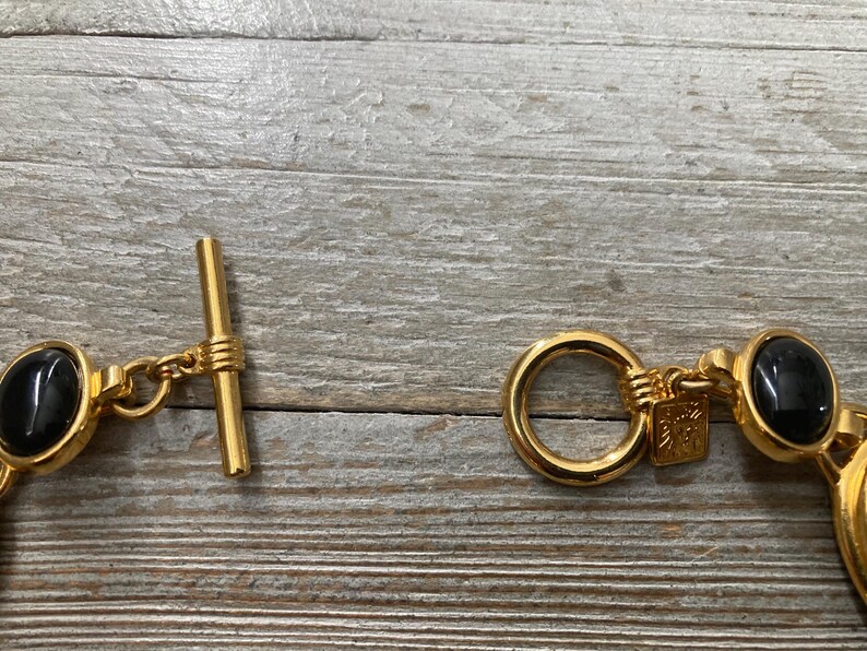 Pode incluir: Pulseira em tom dourado com pedras ovais pretas e fecho de correr.
