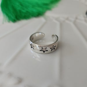 May include: Silver toe ring with three star cutouts. The ring is open ended and adjustable.