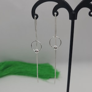 May include: Silver dangle earrings with a small circle and bead detail.