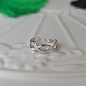 Peut inclure: Une bague d'orteil en argent avec un motif tressé.