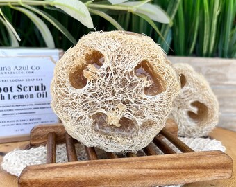 May include: A loofah soap bar with a brown, gel-like soap inside. The soap bar is labeled "Foot Scrub with Lemon Oil" and is made by "Luna Azul Co."