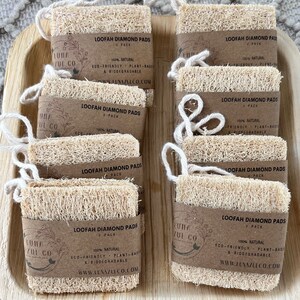 May include: A close-up of ten natural loofah diamond pads, each with a brown paper label that reads "Loofah Diamond Pads" and "Luna Zui Co.". The labels also state that the pads are 100% natural, eco-friendly, plant-based, and biodegradable.