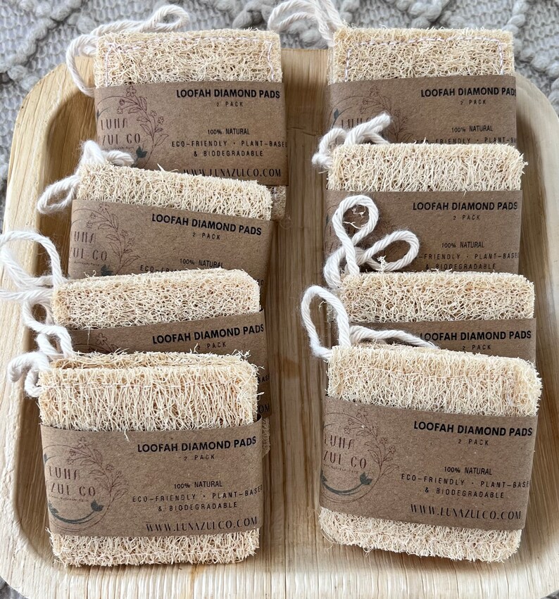 May include: A close-up of ten natural loofah diamond pads, each with a brown paper label that reads "Loofah Diamond Pads" and "Luna Zui Co.". The labels also state that the pads are 100% natural, eco-friendly, plant-based, and biodegradable.
