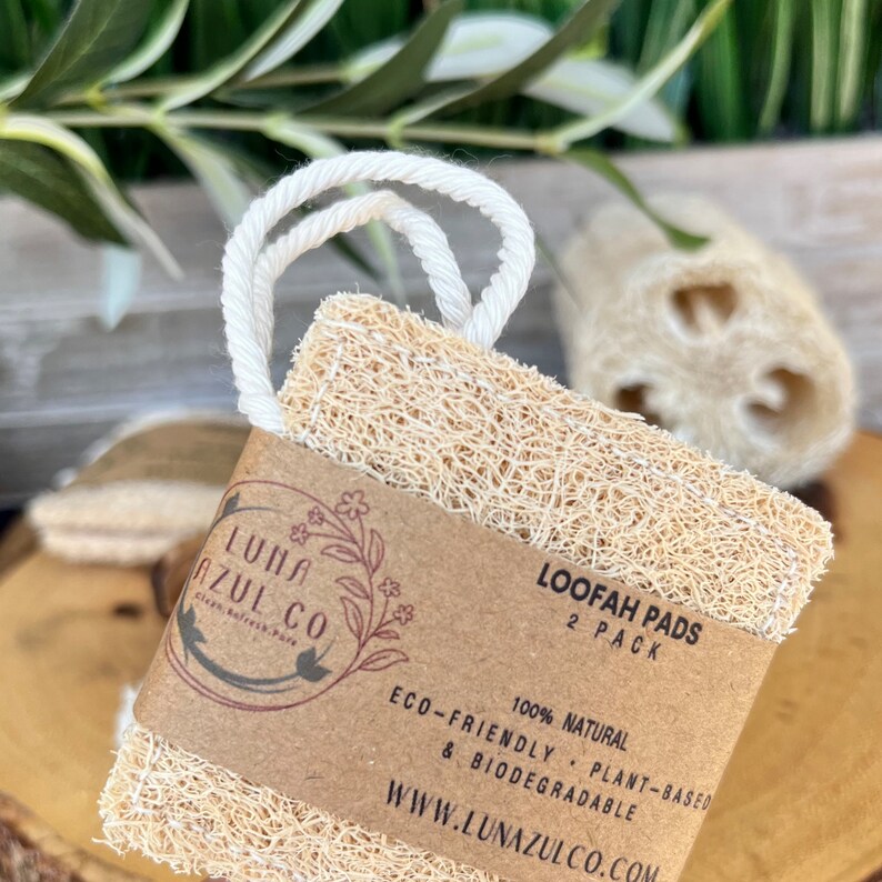 May include: Two natural loofah pads in a 2-pack, with a brown paper label that reads "Loopah Pads 2 Pack 100% Natural Eco-Friendly, Plant-Based & Biodegradable www.lunazulco.com".