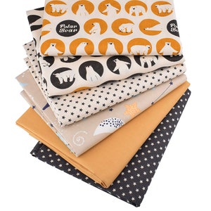 May include: A stack of fabric pieces with various patterns. One fabric features white polar bears in orange circles with the text "Polar Bear". Other fabrics have star, cloud, and solid color designs. The fabrics are in shades of beige, orange, and navy blue.