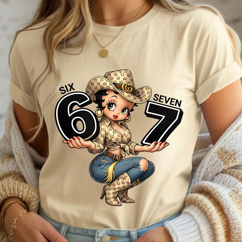 May include: A beige t-shirt featuring a cartoon cowgirl holding the numbers "6" and "7". The cowgirl wears a cowboy hat and a patterned shirt, with blue jeans and boots. The words "SIX" and "SEVEN" are above the numbers.