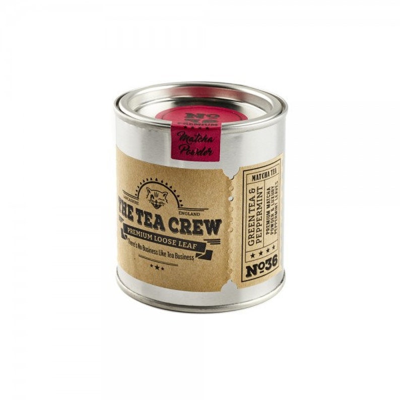 May include: A silver tin with a brown label that reads "The Tea Crew" and "Premium Loose Leaf". The label also has a small illustration of a cat. The tin is labeled "Green Tea & Peppermint" and "No. 36".
