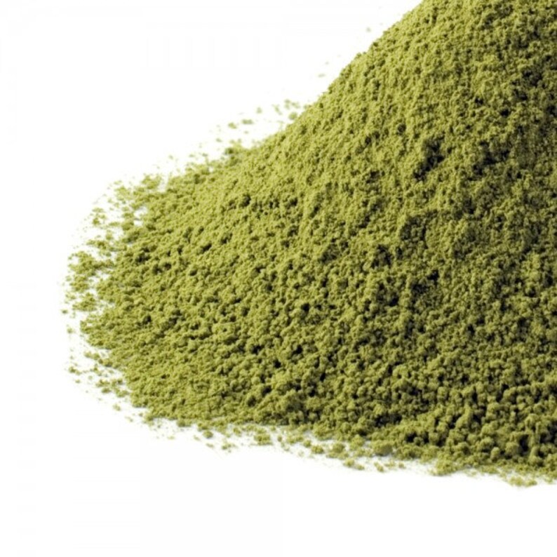 May include: A close-up of a pile of green matcha powder. The powder is finely ground and has a light, airy texture.
