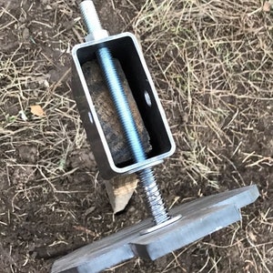 May include: A metal post support with a threaded rod and a square base plate. The rod is threaded through a metal bracket and secured with a nut. The base plate has a star-shaped design.