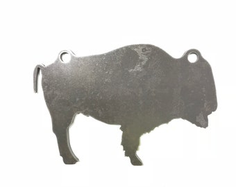 May include: A metal cutout of a bison, with a distressed finish. The bison is standing on all four legs, with its head turned to the side. There are two holes at the top of the cutout, which could be used for hanging.