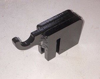 May include: Black metal hook with a unique design. The hook is shaped like an elephant's trunk and has a flat base.