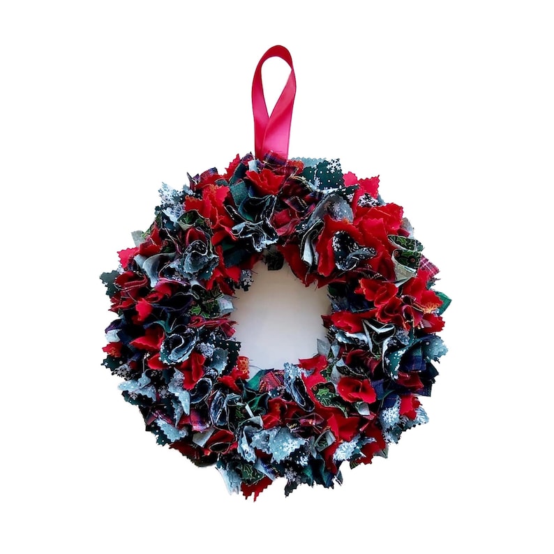 Op de afbeelding: Een rode, groene en blauwe stoffen kerstkrans met een rood lint.
