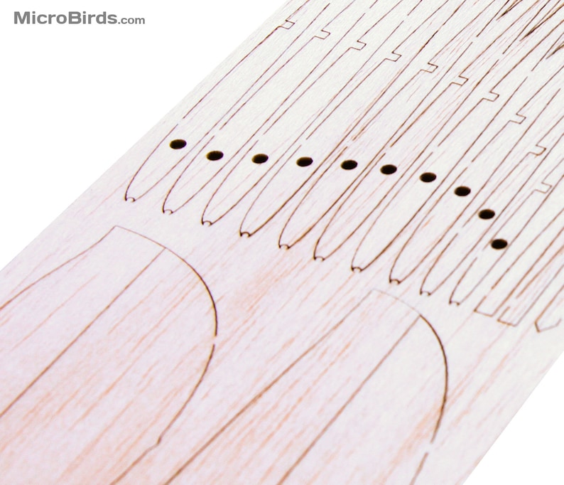 Puede incluir: Primer plano de una pieza artesanal de madera clara con l&iacute;neas grabadas y peque&ntilde;os agujeros. El dise&ntilde;o incluye formas curvas y l&iacute;neas paralelas, posiblemente para un proyecto de bricolaje o modelado. El texto "MicroBirds.com" est&aacute; en la esquina superior izquierda.