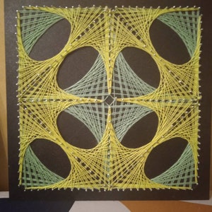 May include: A geometric string art piece with a black background. The design features four overlapping circles created with yellow and green string.