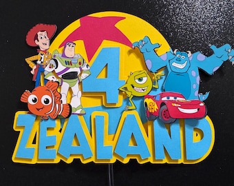 May include: A multi-layered cake topper featuring a large yellow circle with a red star, a blue number 4, and the name ZEALAND in blue letters. The design includes cutouts of Woody, Buzz Lightyear, Nemo, Mike Wazowski, Sulley, and Lightning McQueen.