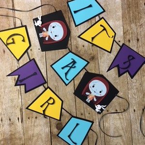 Op de afbeelding: Een kleurrijk spandoek met het woord "GIRL" gespeld in zwarte letters op gele, paarse en blauwe ruitvormige papieren uitsnijdingen. De banner bevat ook twee afbeeldingen van Sally uit The Nightmare Before Christmas.