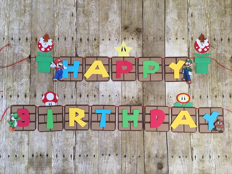 May include: A colourful banner with the words "Happy Birthday" in a brick pattern. The banner features characters from the video game Super Mario Bros., including Mario, Luigi, and a Goomba.