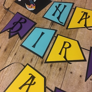 Op de afbeelding: Een kleurrijk papieren banner met de woorden "Happy Birthday" in zwarte letters. De banner is versierd met een zwart silhouet van Sally uit The Nightmare Before Christmas.
