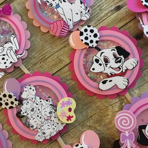 May include: A set of six Dalmatian-themed cupcake toppers. Each topper features a different Dalmatian design with pink, purple, and white accents. The toppers are perfect for a Dalmatian-themed party.