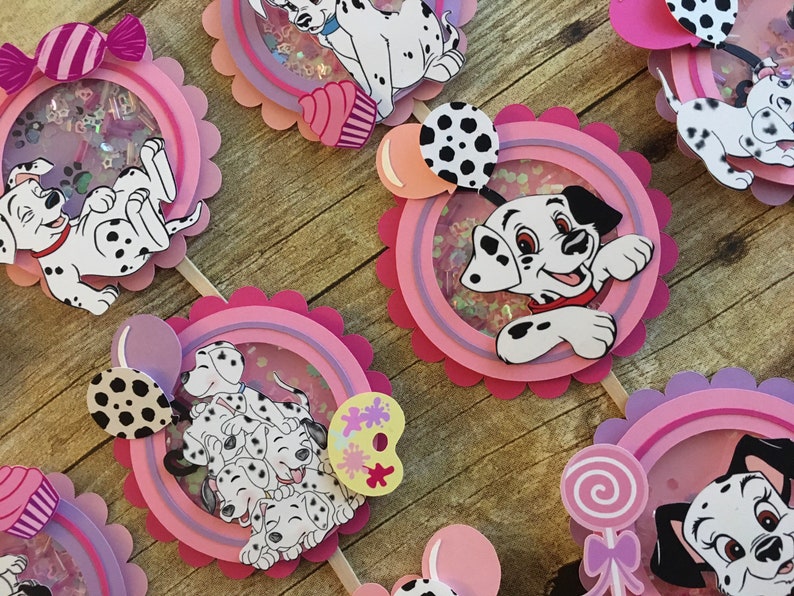 May include: A set of six Dalmatian-themed cupcake toppers. Each topper features a different Dalmatian design with pink, purple, and white accents. The toppers are perfect for a Dalmatian-themed party.