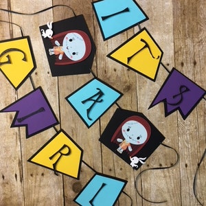 Op de afbeelding: Een zwart-witte banner met het woord "Girl" gespeld in kleurrijke letters. Elke letter staat op een aparte vlag. De vlaggen zijn in de kleuren paars, geel, blauw en zwart. De zwarte vlaggen bevatten een cartoonafbeelding van een meisje met rood haar en een witte jurk. Het meisje houdt een wit konijn vast.