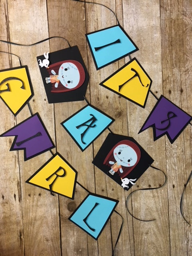 Op de afbeelding: Een zwart-witte banner met het woord "Girl" gespeld in kleurrijke letters. Elke letter staat op een aparte vlag. De vlaggen zijn in de kleuren paars, geel, blauw en zwart. De zwarte vlaggen bevatten een cartoonafbeelding van een meisje met rood haar en een witte jurk. Het meisje houdt een wit konijn vast.