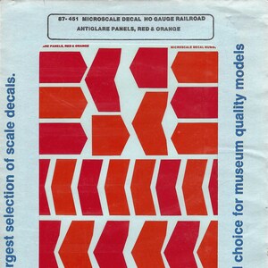 May include: A sheet of red and orange decals for HO gauge railroad anti-glare panels. The decals are arranged in rows and columns, with a variety of shapes and sizes. The sheet is labeled "87-451 Microscale Decal HO Gauge Railroad Anti-Glare Panels, Red & Orange".