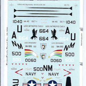 Puede incluir: Una hoja de calcomanías para USN A-4E Skyhawks, con varias marcas e insignias. Las calcomanías incluyen números de avión, designaciones de escuadrón y la palabra "NAVY". La combinación de colores es principalmente azul, blanco y negro.