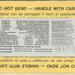 Könnte beinhalten: Ein weißer Aufkleber mit schwarzem Text, der "NICHT BEUGEN - MIT SORGFALT HANDHABEN" lautet. Der Aufkleber enthält Informationen über die Kapazität, das Gewicht und die Abmessungen eines Güterwagens. Er enthält auch Anweisungen zum Schließen der Tür, zum Belüften des Güterwagens und zur Verwendung der Westinghouse-Automatikbremse. Der Aufkleber ist auf gelbem Hintergrund gedruckt.