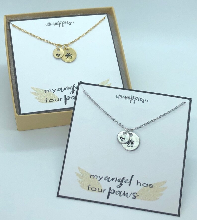 Puede incluir: Dos collares de plata con un dije de coraz&oacute;n y huella de pata. Los collares se muestran en cajas con el texto "mi &aacute;ngel tiene cuatro patas".