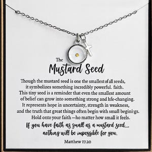 May include: A silver-toned necklace featuring a pendant with a mustard seed and a small cross charm. The pendant is round with a clear center. The card behind the necklace has text about faith.