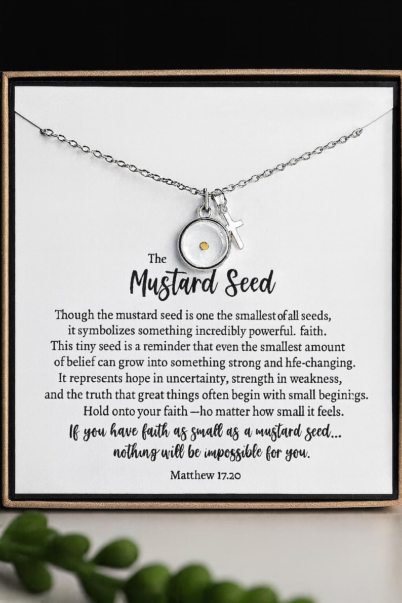 May include: A silver-toned necklace featuring a pendant with a mustard seed and a small cross charm. The pendant is round with a clear center. The card behind the necklace has text about faith.