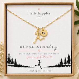 Könnte beinhalten: Eine goldfarbene Halskette mit einem Läufer-Anhänger und einem kleinen runden Anhänger mit einem schwarzen Herz. Die Präsentationskarte zeigt: little happies co., cross country, EVERY MILE. EVERY HILL. EVERY VICTORY. you've got this!, und littlehappiesco.com.