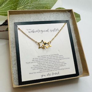 May include: A gold necklace with two intertwined star charms in a gift box with a card that reads "To My unbiological sister" and a message about friendship and love. The card says "We started out as best friends. As time has passed, we have become sisters. We have shared our greatest joys and sorrows. Thank you for being a constant source of encouragement & love. I know you will never bail on me. You see the best in me & I see the best in you. It's a blessing to have someone always on your side. Let's remember how important our friendship is. and never take it for granted. Wear this necklace as a reminder of our friendship & know you are loved."