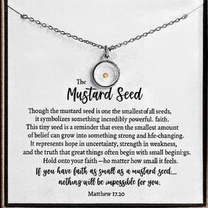 May include: Silver-toned necklace with a circular pendant containing a mustard seed. The pendant hangs from a delicate chain. The card behind the necklace has text that reads "The Mustard Seed" and a quote from Matthew 17:20.