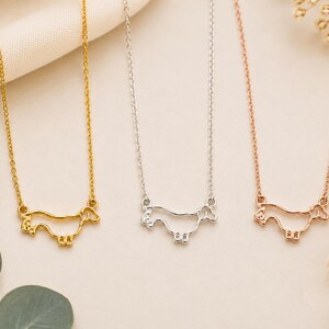 May include: Three necklaces featuring a minimalist outline pendant of a dachshund dog. The set includes one gold-toned necklace, one silver-toned necklace, and one rose gold-toned necklace, each with a delicate chain and a dog-shaped charm.