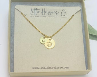 May include: Gold necklace with a basketball charm and a heart charm. The necklace is in a box with the text "Little Happies Co. It is more blessed to give than to receive" and "www.littlehappiesco.com".
