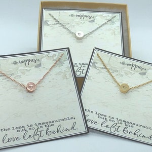 May include: Three necklaces with small heart charms on a white background. The necklaces are silver, gold, and rose gold. The necklaces are in boxes with the text "Little Happier" and the quote "The loss is immeasurable, but so is the love left behind."