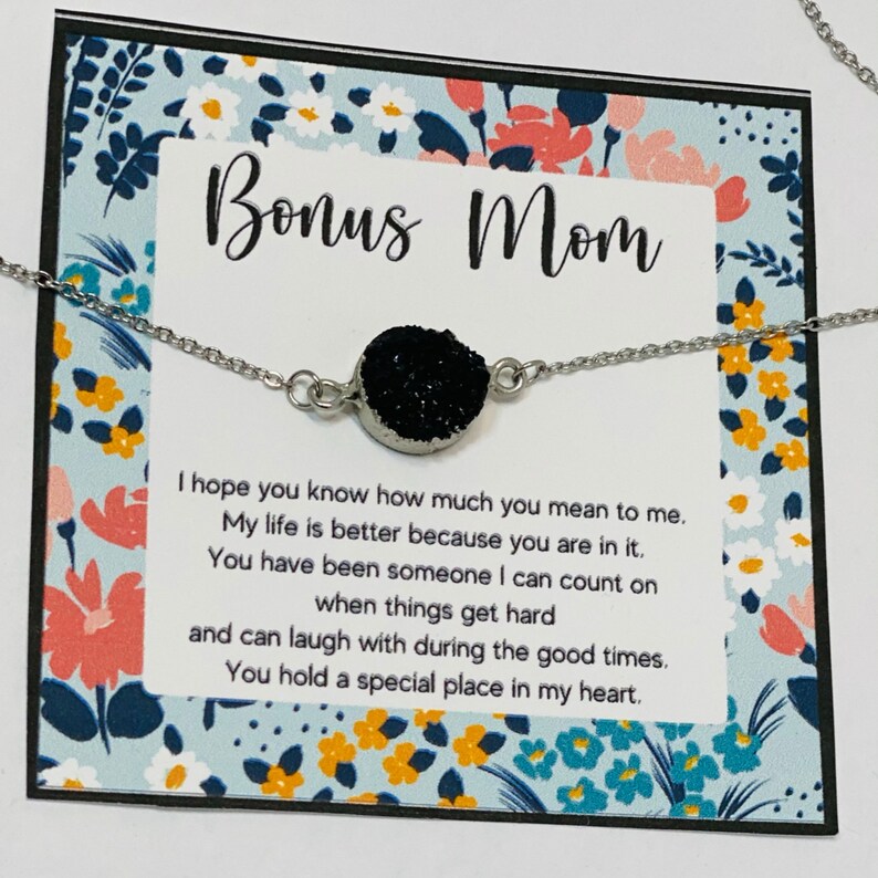 May include: A silver necklace with a black sparkly charm and a card that reads "Bonus Mom" with a message about how much the recipient means to the giver.