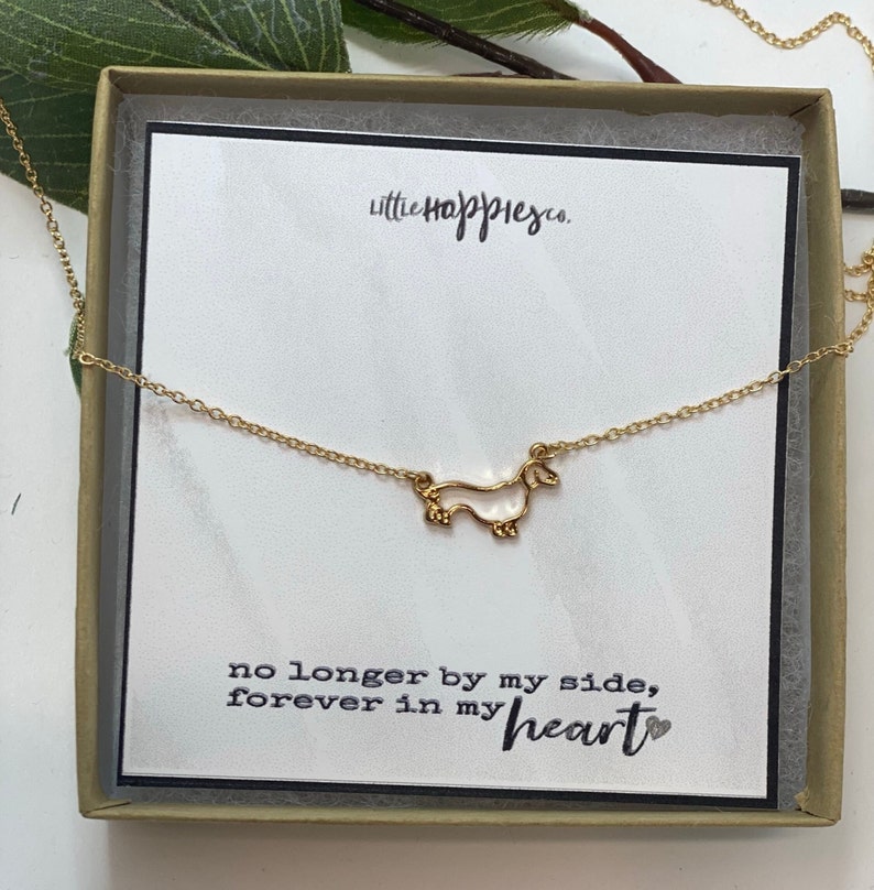 May include: A gold necklace with a dachshund charm and a card that reads "no longer by my side, forever in my heart".